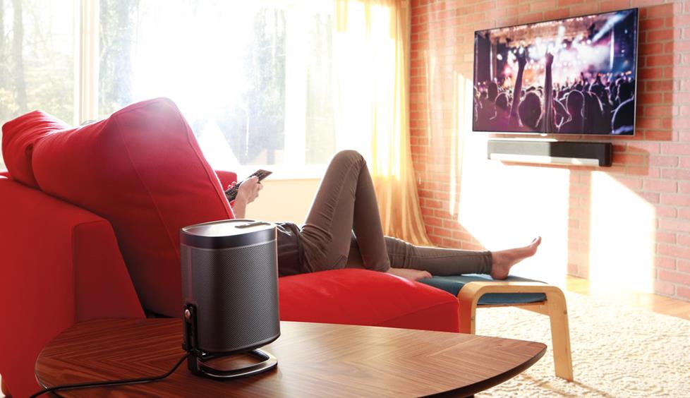 Woman on her couch watching TV with a Sonos PlayBar