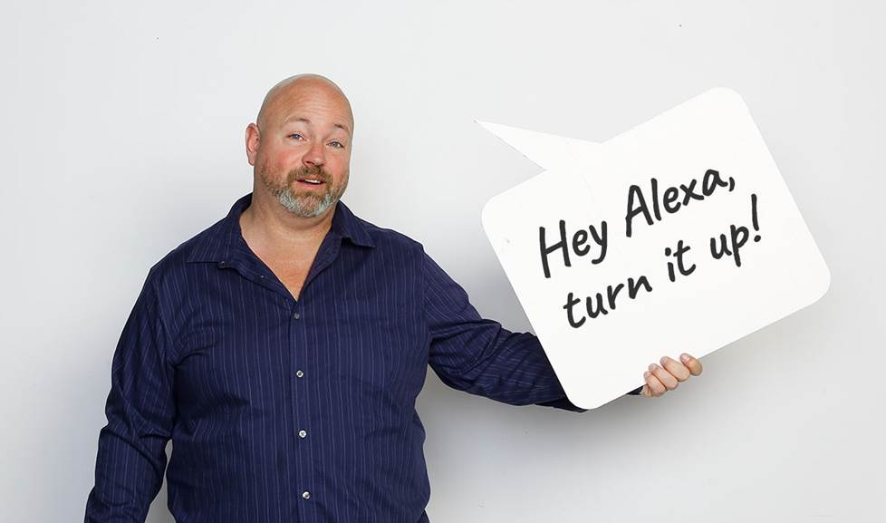 man holds speech bubble that says "Hey Alexa, turn it up!"
