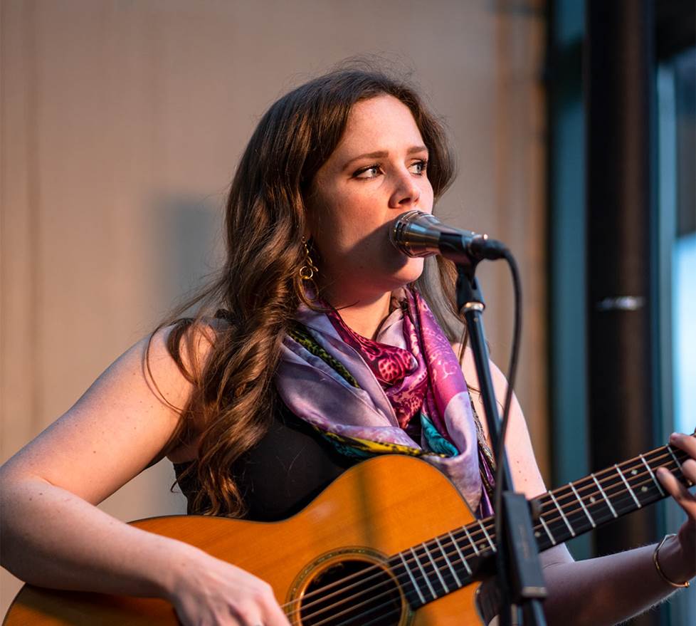 Female guitarist singing into mic