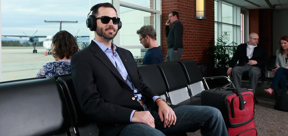 Man wearing noise-canceling headphones at the airport.