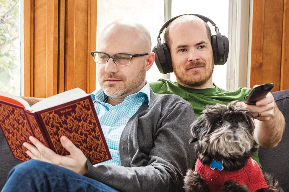 couple on couch with dog reading and listening to TV with headphones