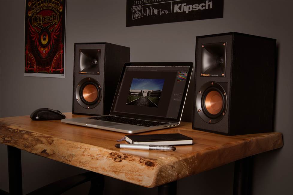 Klipsch desktop speakers sitting on a desk next to a computer.