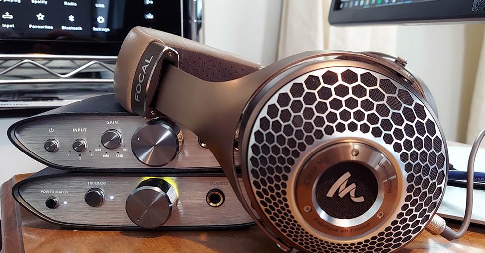 Image of Focal Clear MG beside two amps.