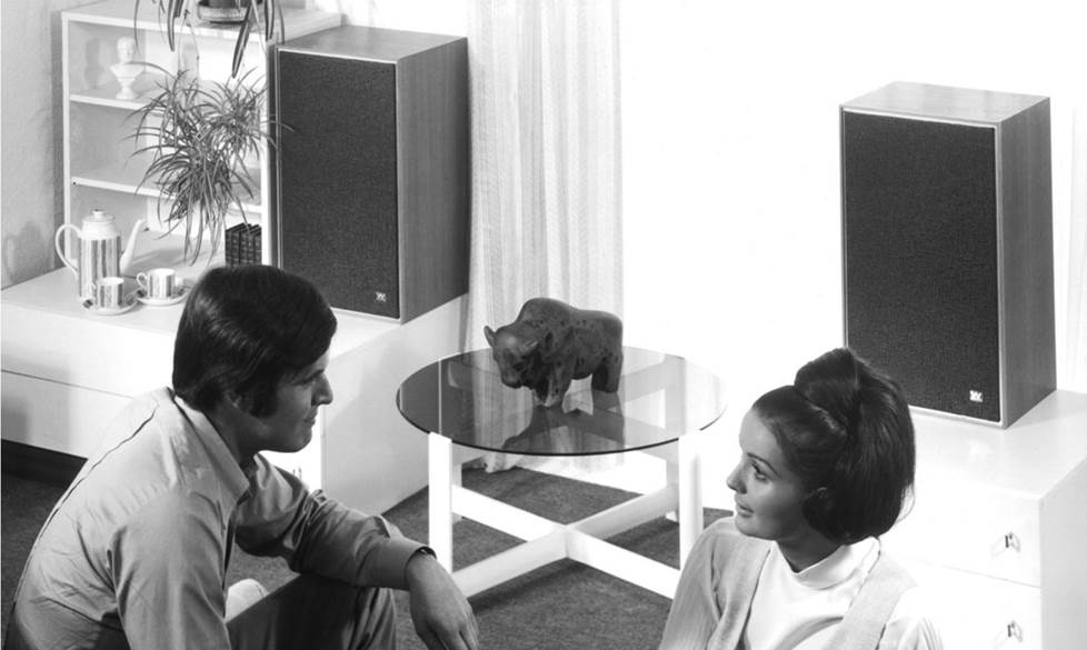 Vintage photo of two people sitting in an old room listening to two vintage Wharfedale Linton speakers.