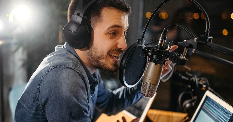 Man speaking into a microphone in front of a computer