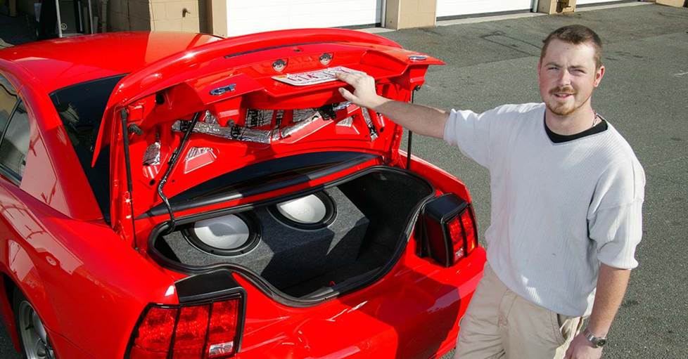 a subwoofer box with two subs, in the trunk of a Ford Mustang