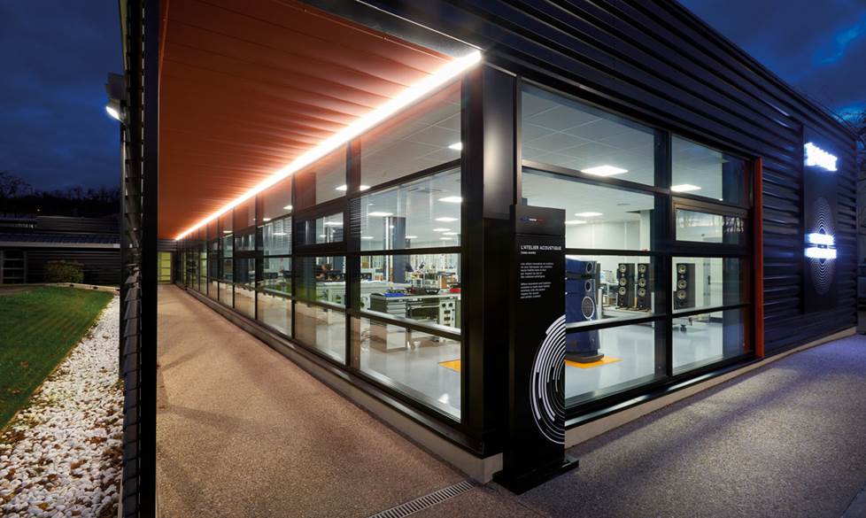 Photo of a building at night with glass windows looking into a lighted testing room.