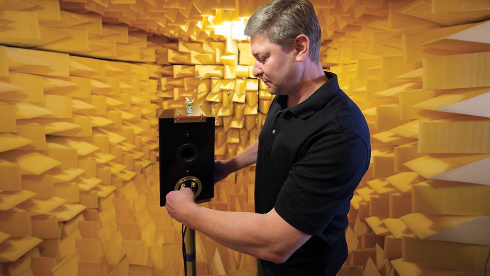 an engineer connecting a stand-mounted speaker in an anechoic chanber