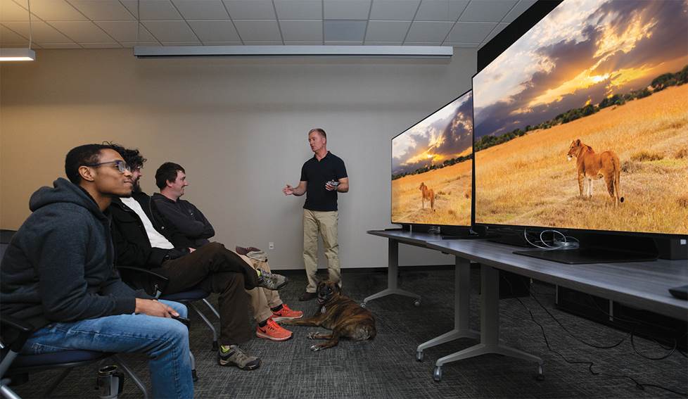Group of employee comparing 2 tv sets with another person presenting