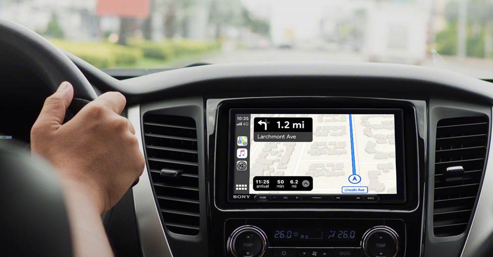 photo of the Sony XAV-AX6000 installed in a car that is driving down the road. The Sony is displaying Apple Car play, showing the maps application.