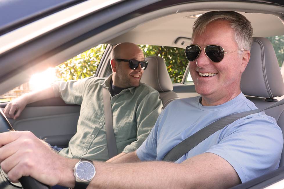 2 men sitting in a car enjoying the Atmos sound