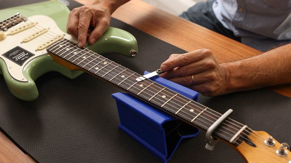 Hands on a guitar, measuring neck relief