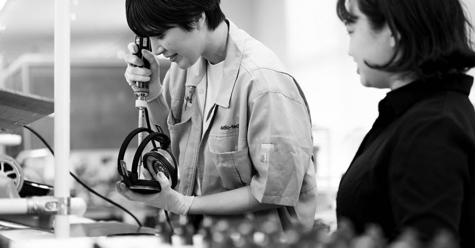 Shiwako working with another worker on a pair of headphones