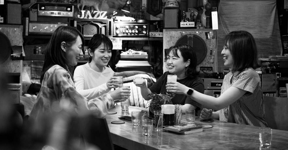 Cheers! Having a drink with friends around a table surrounded by a wall of electronics