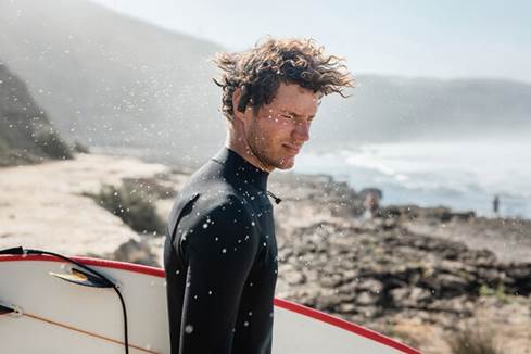Surfer wearing the JBL Endurance Peak 3 hook-style earbuds