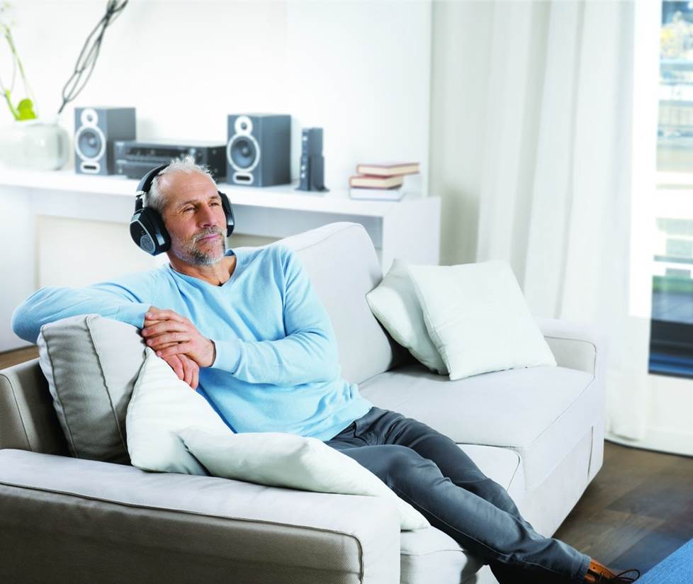 A man watching TV wearing Sennheiser Wireless TV headphones