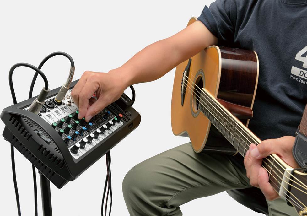 acoustic guitar player adjusting Yamaha StagePas mixer